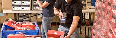 A Man Using A Handheld Barcode Scanner To Scan A Package